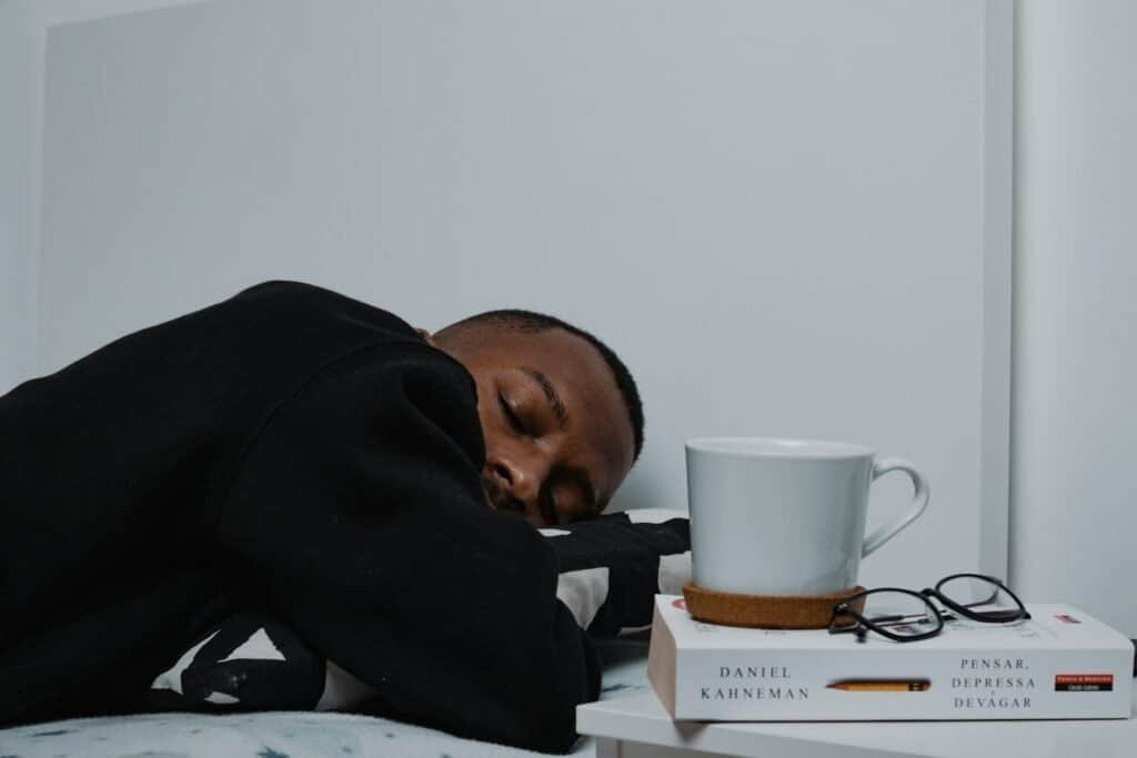 Dormindo com livros e acessórios de leitura ao lado, ambiente tranquilo e confortável.