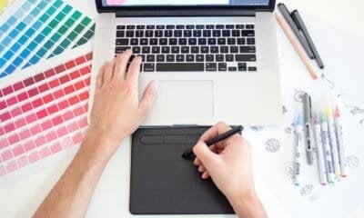 Réplica de mão de designer gráfico usando tablet digital e laptop para criar arte digital.