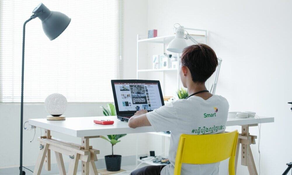 Tecnologia moderna em escritório com jovem usando laptop, produtividade digital, ambiente de trabalho clean.