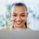 Pessoa jovem usando computador com sorriso, tecnologia e inovação na rotina.