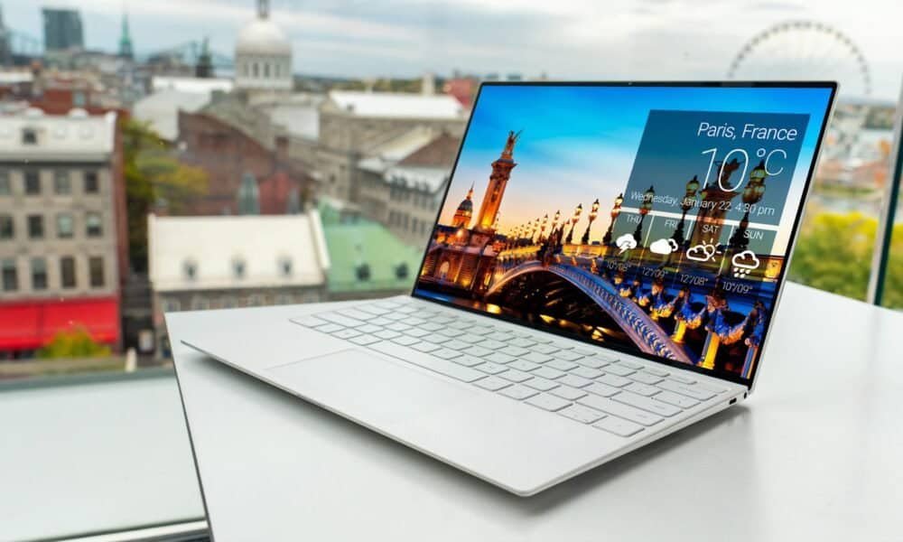 Laptop com tela exibindo previsão do tempo para Paris, França, em ambiente de escritório moderno.