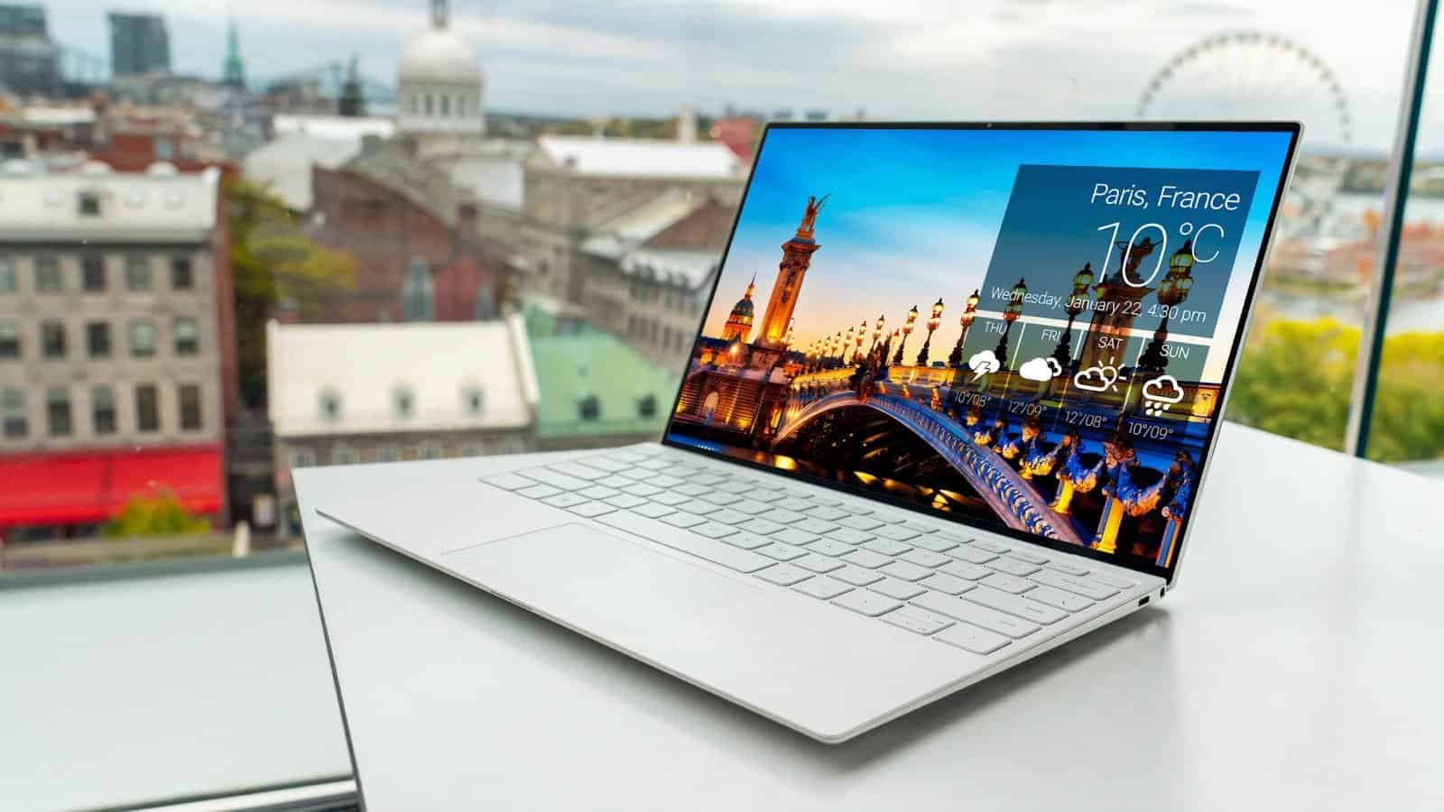 Laptop com tela exibindo previsão do tempo para Paris, França, em ambiente de escritório moderno.