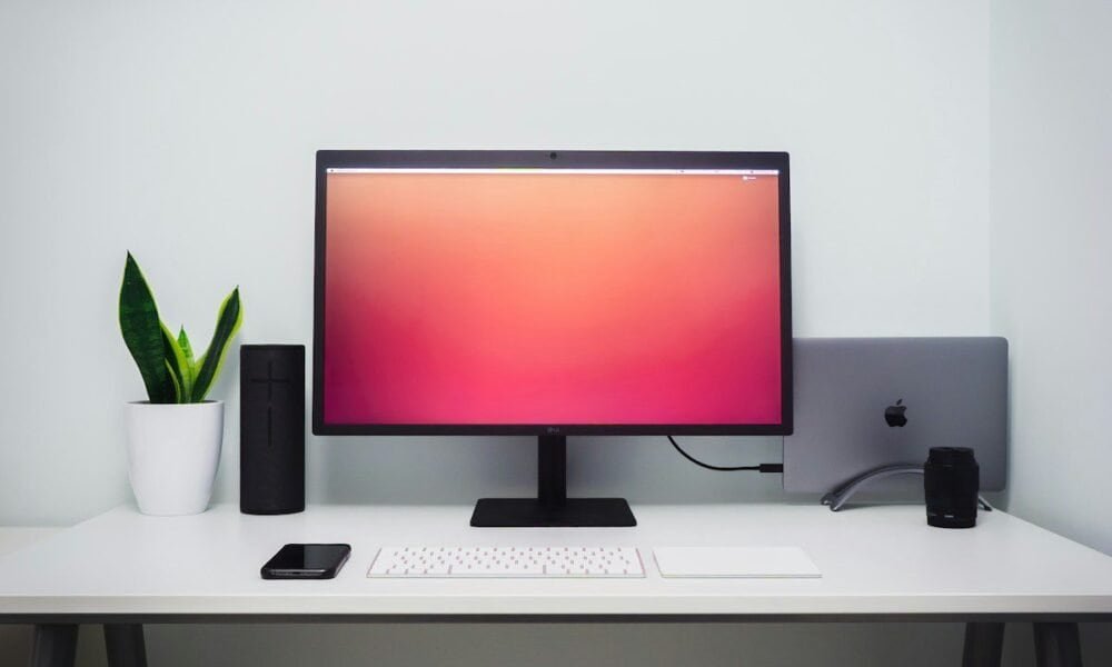 Monitor de computador com tela de fundo colorida e acessórios de tecnologia.