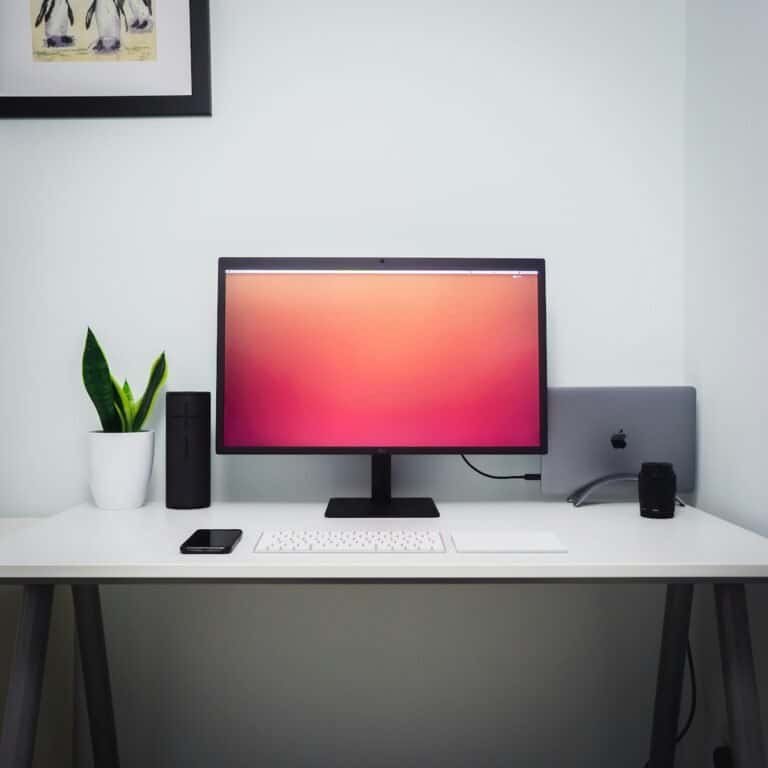 Monitor de computador com tela de fundo colorida e acessórios de tecnologia.