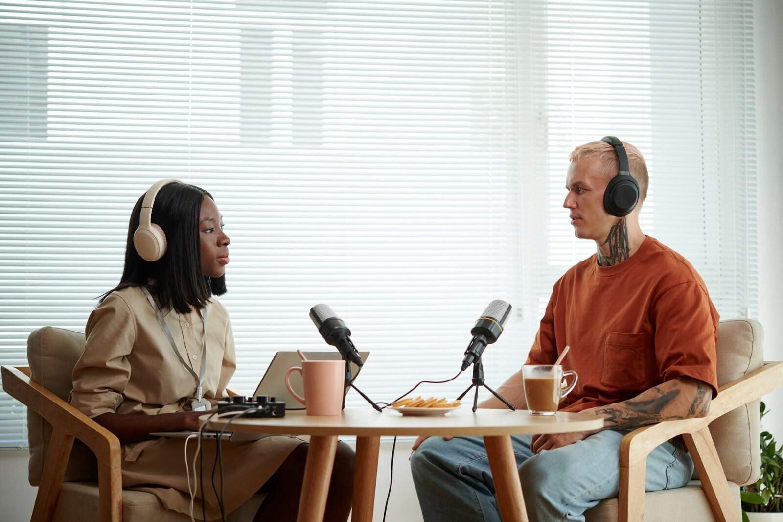 Áudio de podcast com duas pessoas conversando, usando fones de ouvido, em ambiente de estúdio.