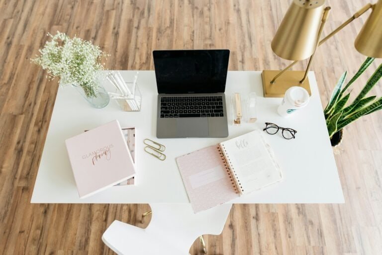 Cabine de escritório com laptop, livros e objetos decorativos elegantes.