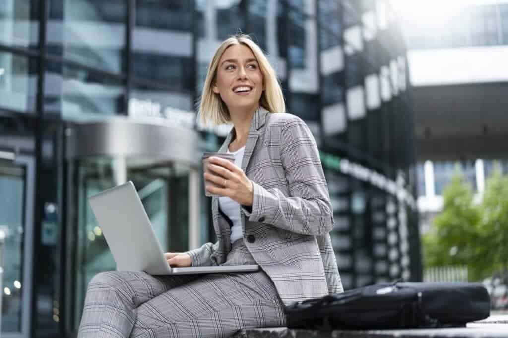 Laptop e smartphone em ambiente urbano, mulher feliz usando tecnologia moderna.
