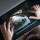 Fotografia de uma pessoa editando uma imagem em tablet com aplicativo de edição de fotos, mostrando ajustes de luz e contraste.