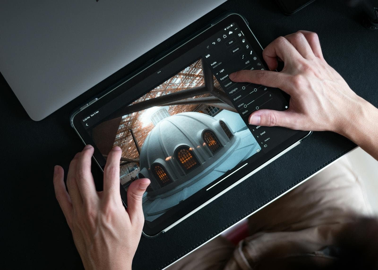 Fotografia de uma pessoa editando uma imagem em tablet com aplicativo de edição de fotos, mostrando ajustes de luz e contraste.