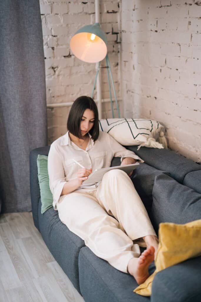 Confortável pessoa usando tecnologia em casa, leitura em tablet, ambiente acolhedor e moderno.