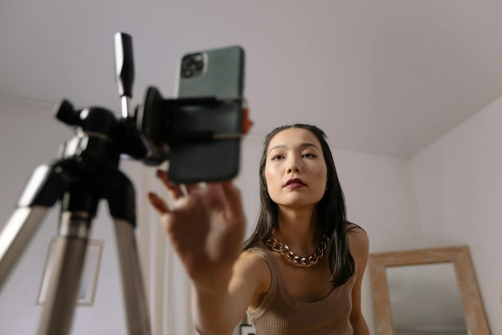 Iphone com suporte para gravação de vídeos e selfies, mulher fazendo TikTok ou vlog, tecnologia de celular e vídeo.