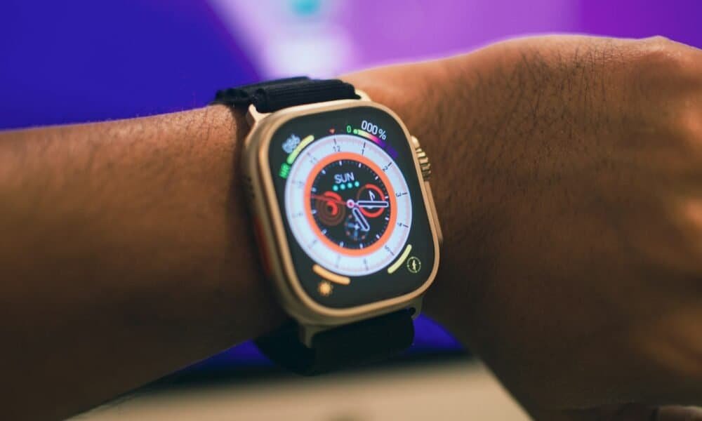 Carregador de smartwatch com pulseira preta em pulso humano.