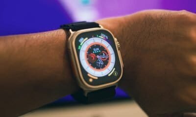 Carregador de smartwatch com pulseira preta em pulso humano.