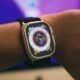 Carregador de smartwatch com pulseira preta em pulso humano.