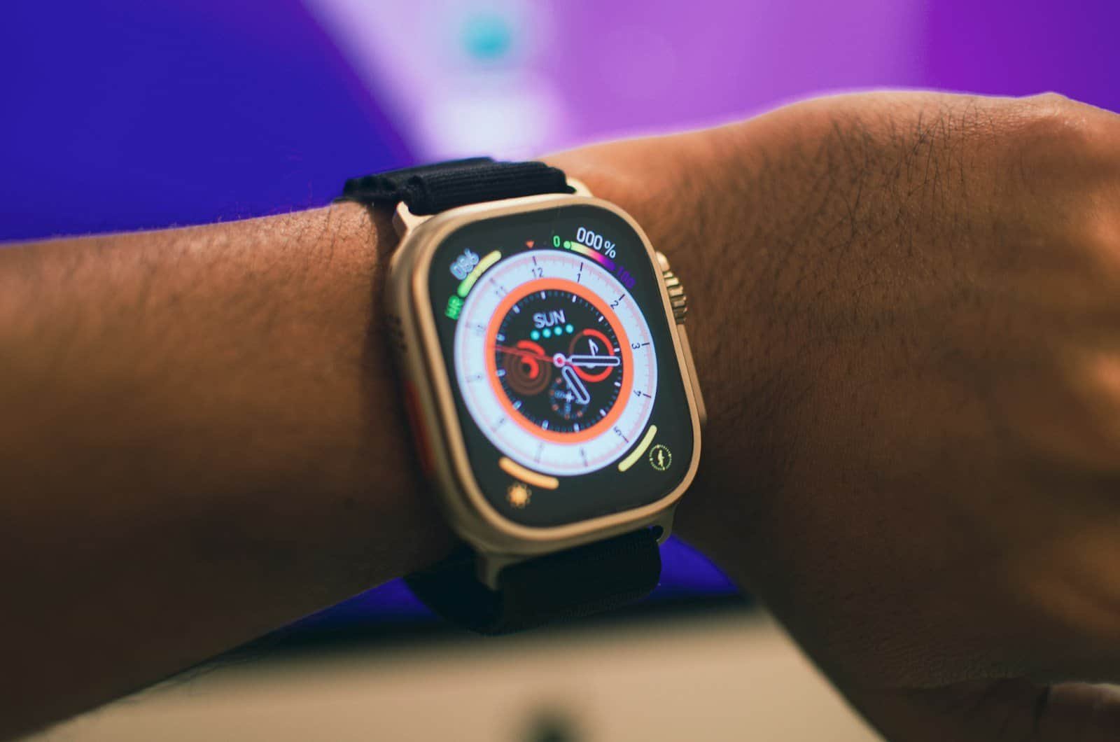 Carregador de smartwatch com pulseira preta em pulso humano.