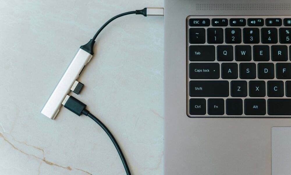 Conector USB-C tipo C ligado em laptop com teclado iluminado, tecnologia e inovação.