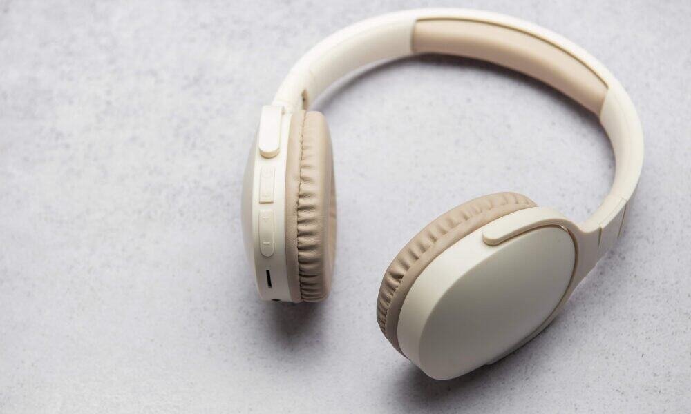 Fone de ouvido sem fio branco sobre fundo neutro.
