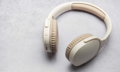 Fone de ouvido sem fio branco sobre fundo neutro.