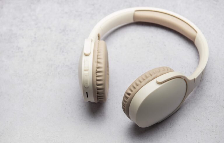 Fone de ouvido sem fio branco sobre fundo neutro.