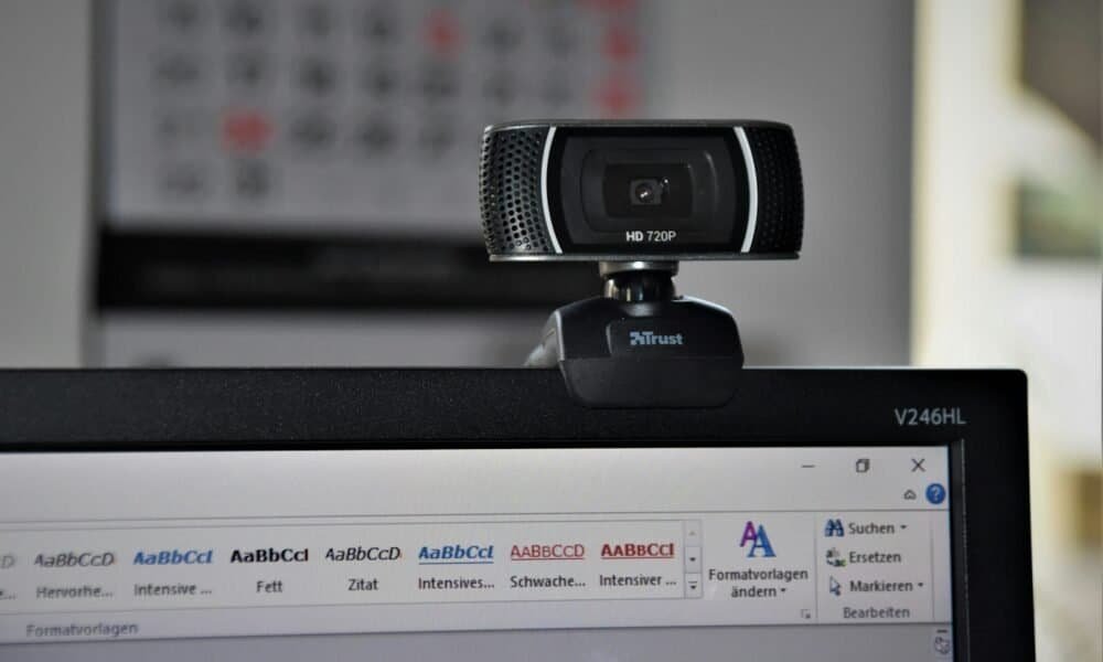 Webcam de alta definição conectada a um computador com software de edição de texto aberto, ideal para tecnologia, videoconferências e streaming.