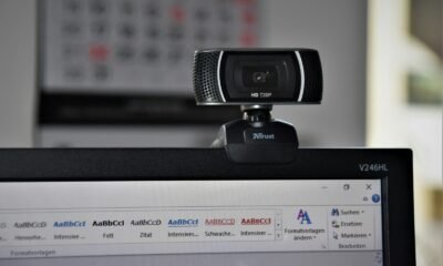 Webcam de alta definição conectada a um computador com software de edição de texto aberto, ideal para tecnologia, videoconferências e streaming.