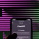 Imagem de um smartphone exibindo uma tela de chat com ChatGPT, fundo com linhas coloridas em rosa e verde.