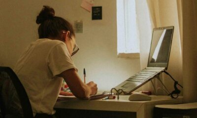 Estudante estudando em frente ao computador em casa, foco em tecnologia e educação online.