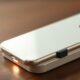 Smartphone Apple iPhone com carregador sem fio sobre mesa de madeira disponível no Seu Guia de Tecnologia.