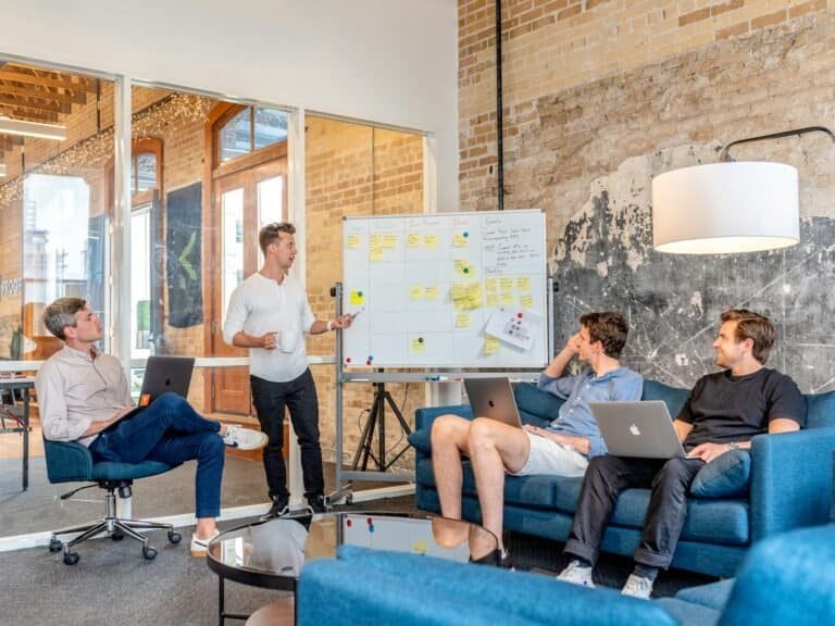 Planejamento de equipe com laptop e quadro branco em ambiente de escritório moderno.