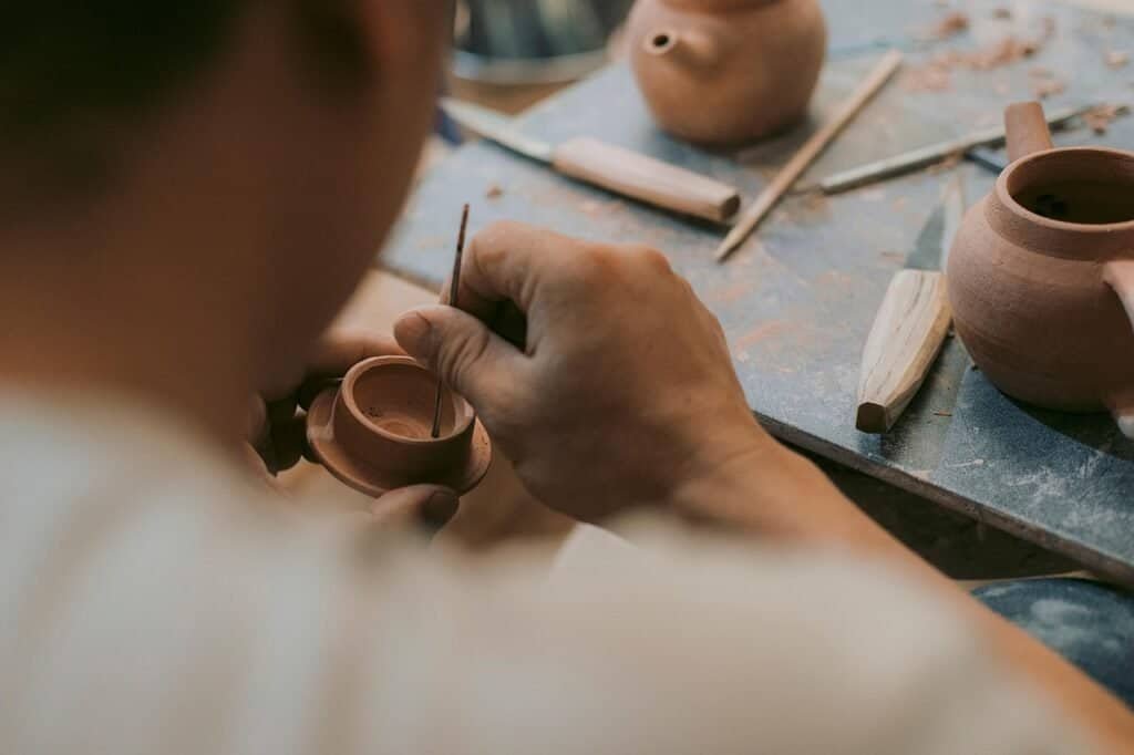 Ferramenteiro moldando uma peça de cerâmica artesanalmente.