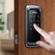 Tela de controle de acesso digital com teclado numérico em porta de madeira.