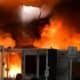 Incêndio em evento com estrutura de feira, grande chame e fumaça de fogo intenso.