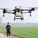 Drone de tecnologia com câmera para filmagens aéreas; piloto controlando drone com controle remoto; inovação em tecnologia de drones.