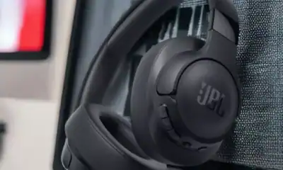 Fone Bluetooth JBL over-ear preto em ambiente de escritório com computador.