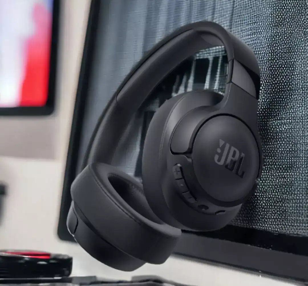 Fone Bluetooth JBL over-ear preto em ambiente de escritório com computador.