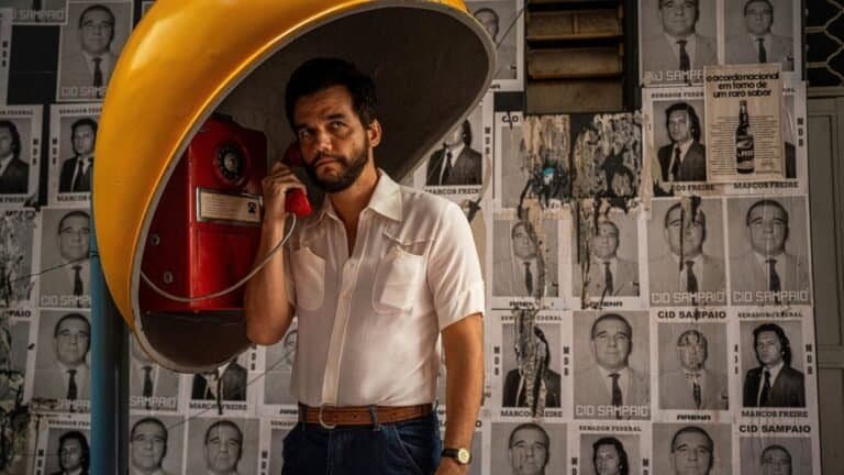 Telefone público antigo em taça, estilo retrô, com fundo de posters políticos preto e branco.