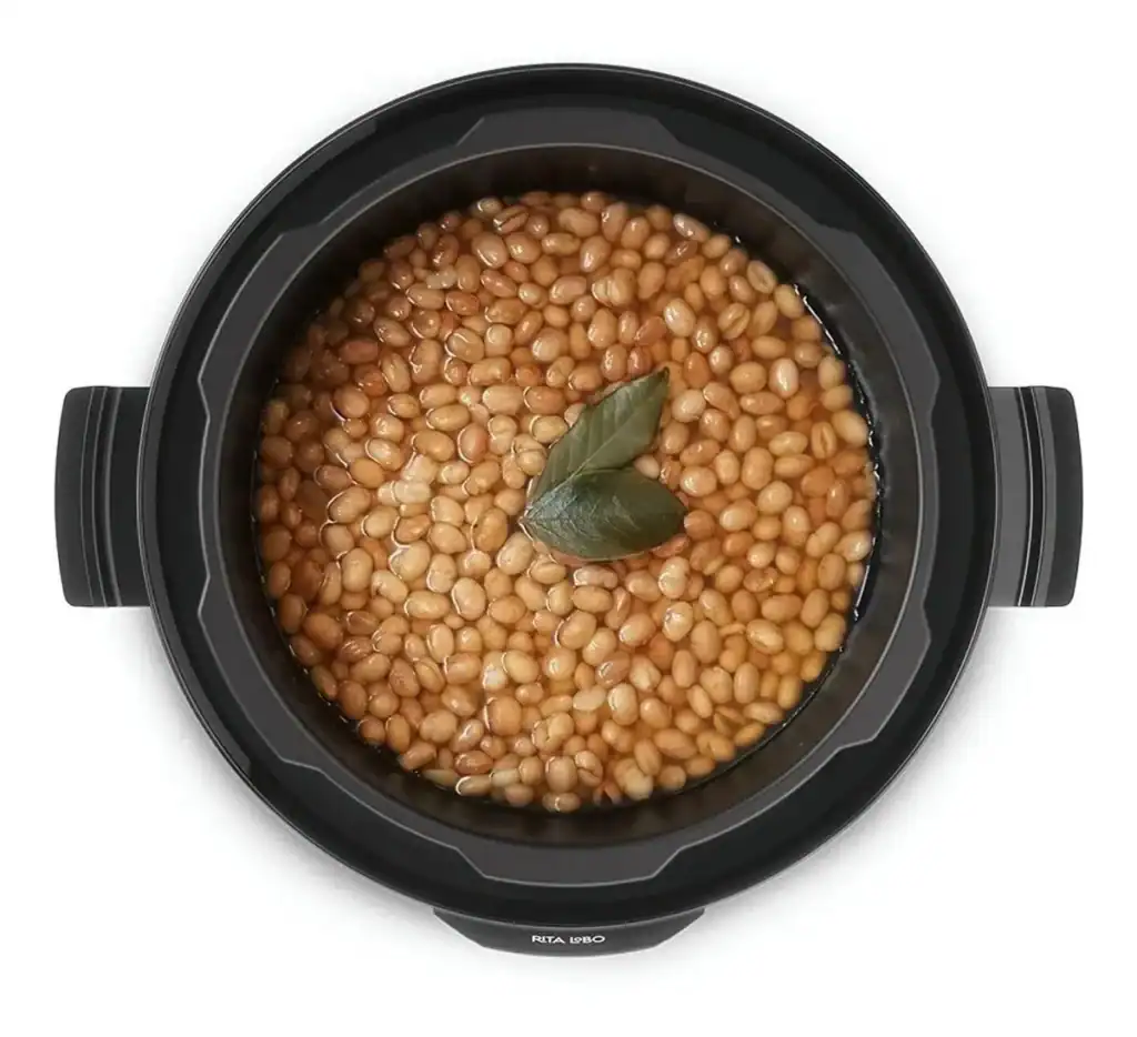 Legumes sendo cozidos na panela de pressão elétrica com folhas de louro.