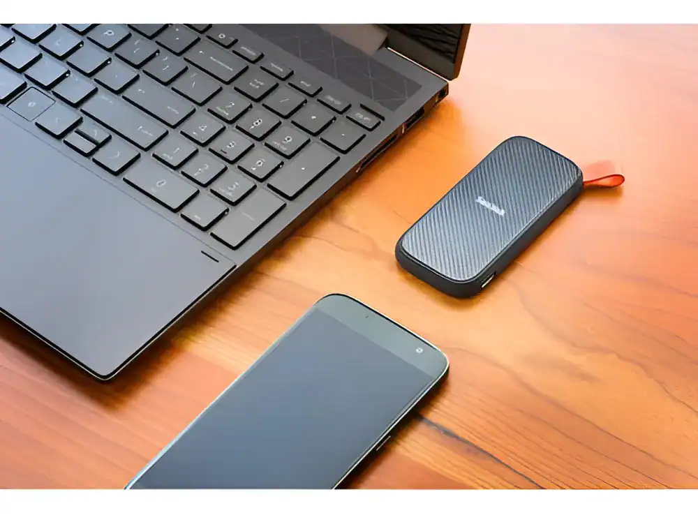 Dispositivo de armazenamento portátil conectado ao laptop e smartphone com tecnologia moderna.