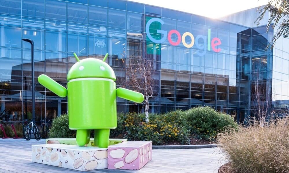 Android em frente ao prédio do Google, símbolo de tecnologia e inovação.