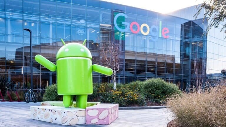 Android em frente ao prédio do Google, símbolo de tecnologia e inovação.