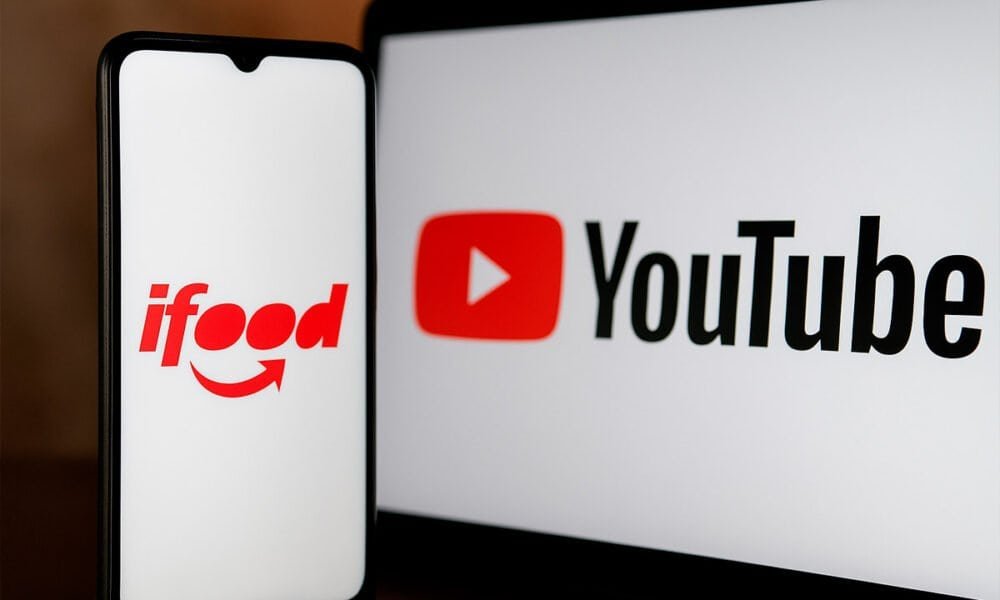 Ifood app na tela do celular e logo do YouTube na tela do monitor.