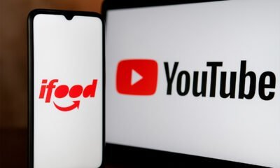 Ifood app na tela do celular e logo do YouTube na tela do monitor.