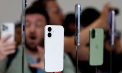 Smartphone branco em exposição com vários modelos ao fundo, tecnologia de smartphones.