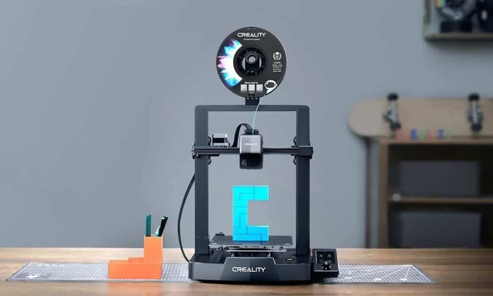 Impressora 3D Criality criando objeto de plástico azul em uma mesa de trabalho.