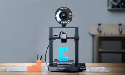 Impressora 3D Criality criando objeto de plástico azul em uma mesa de trabalho.