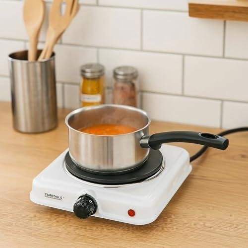 Panela elétrica de cozinha com sopa quente, utensílios de cozinha ao fundo.