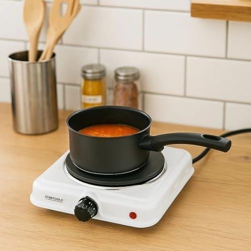 Panela elétrica para cozinhar molho de tomate, utensílios de cozinha ao fundo, cozinha moderna.