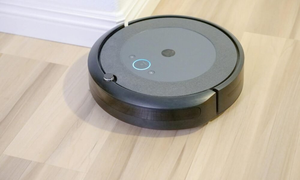 Robô aspirador de pó preto em piso de madeira, tecnologia de limpeza automatizada.