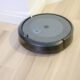 Robô aspirador de pó preto em piso de madeira, tecnologia de limpeza automatizada.