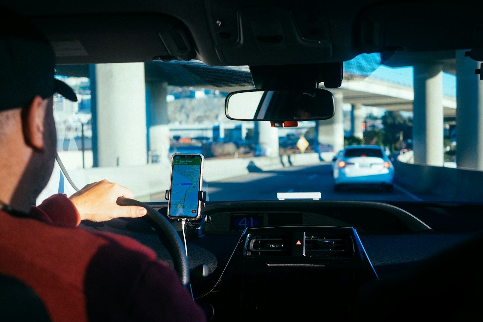 Pessoa usando smartphone no carro, tecnologia de condução autônoma em destaque.